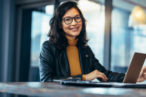 smiling woman sitting at desk with laptop