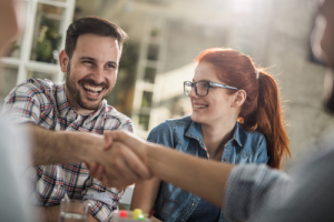 young man and woman shaking hands with someone off camera